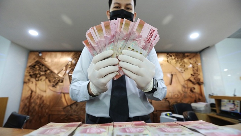 Petugas teller bank menunjukkan uang rupiah di Jakarta. Foto ilustrasi: Beritasatu Photo/Uthan AR