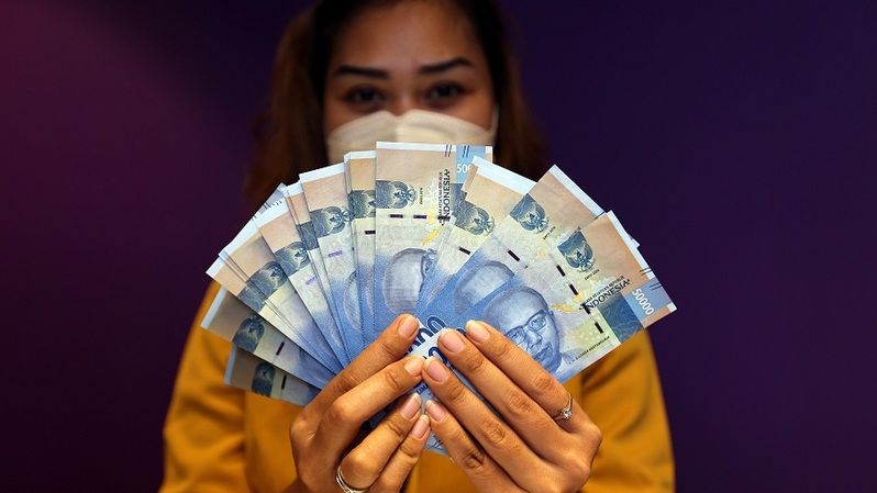 Karyawati memperlihatkan uang rupiah di salah satu bank di Jakarta. Foto ilustrasi: BeritaSatu Photo/Mohammad Defrizal
