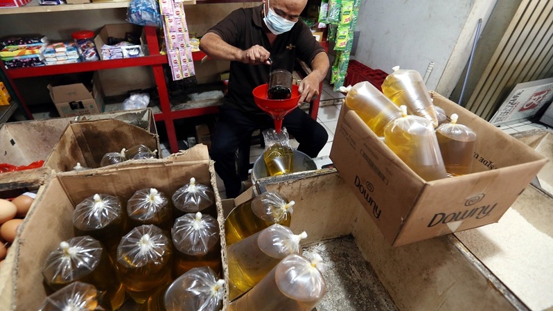 Pedagang minyak goreng eceran menakar minyak goreng curah di warung kelontong di Kemandoran, Jakarta, Rabu (10/2/2022).  Foto ilustrasi: BeritaSatu Photo/Mohammad Defrizal 