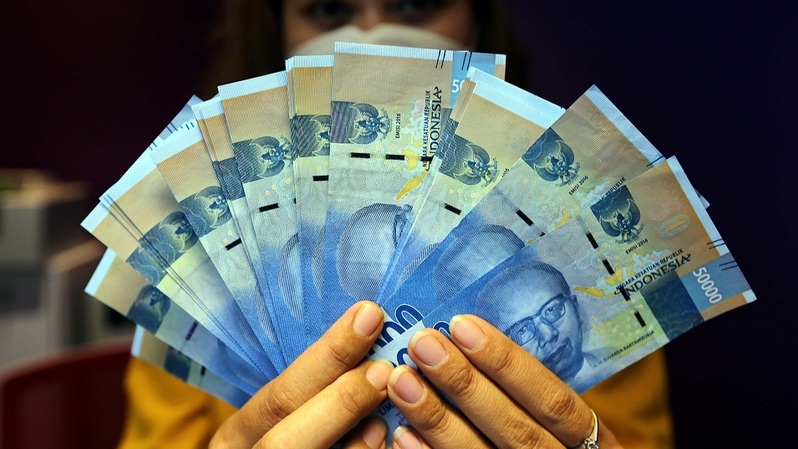 Karyawati memperlihatkan uang rupiah, di Jakarta.  Foto ilustrasi: BeritaSatu Photo/Mohammad Defrizal