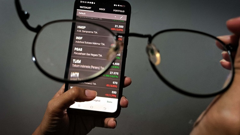 Investor melihat pergerakan harga saham melalui layar ponsel. Foto ilustrasi: BeritaSatu Photo/Mohammad Defrizal