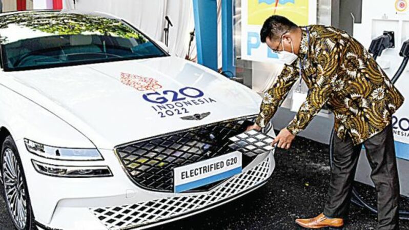 Seorang petugas (kanan) di Nusa Dua, Bali, Jumat (25/2) sedang mengisi ulang baterai mobil listrik setelah peluncuran stasiun pengisian kendaraan listrik umum (SPKLU) yang akan dipakai untuk transportasi resmi pertemuan puncak G20 di Bali akhir Oktober tahun ini. Foto: Investor Daily/SONNY TUMBELAKA / AFP