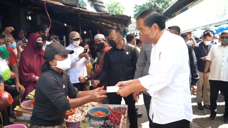 Presiden Joko Widodo saat menyerahkan BLT minyak goreng kepada seorang pedagang. 