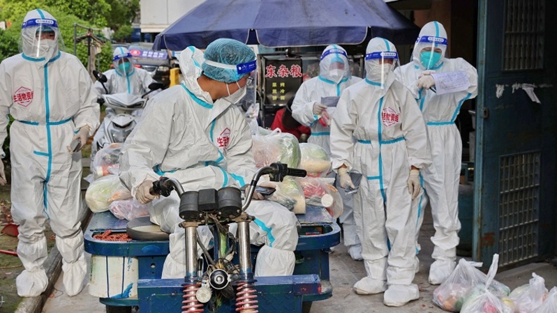 Anggota staf bersiap mengantarkan makanan yang didistribusikan oleh pemerintah setempat, karena penyebaran virus corona Covid-19 di Nantong, Provinsi Jiangsu timur Tiongkok, pada 17 April 2022. (FOTO: STR / AFP)