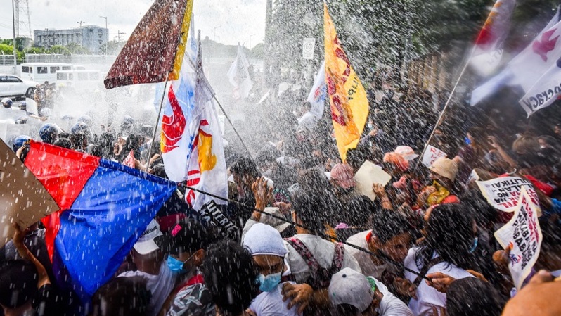 Petugas polisi menggunakan meriam air untuk membubarkan demonstran selama rapat umum di kantor Komisi Hak Asasi Manusia di Quezon, dekat Manila pada 25 Mei 2022. Massa mengecam hasil pemilu 2022 dan aksi unjuk rasa diakhiri dengan bentrokan dengan polisi. (FOTO: MARIA TAN / AFP)