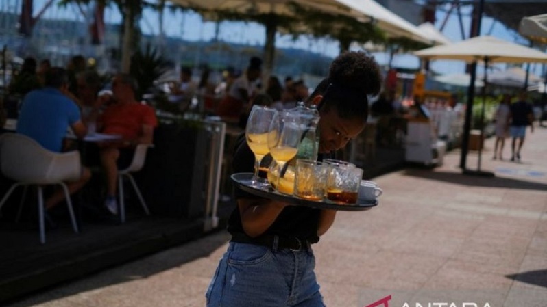 Seorang staf membawa minuman di sebuah restoran di Lisbon, Portugal pada 6 Juni 2022. (FOTO: ANTARA/Reuters/Pedro Nunes/as)