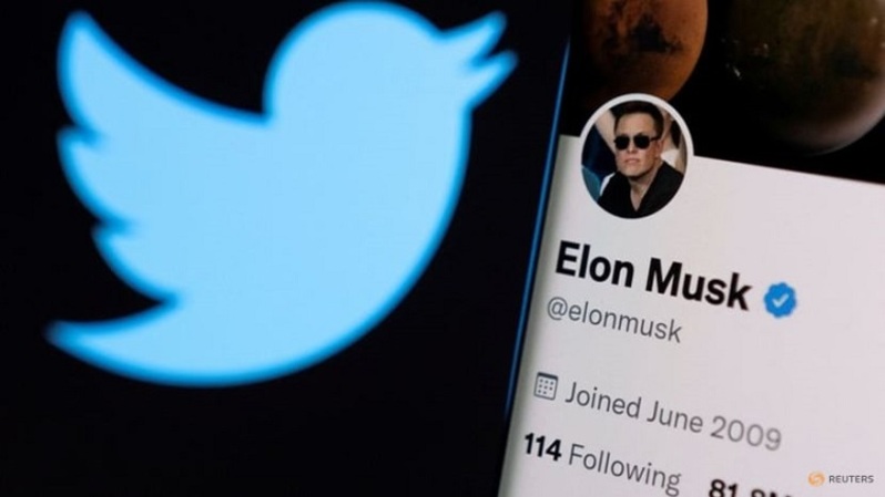 Akun twitter Elon Musk terlihat di ponsel pintar di depan logo Twitter dalam ilustrasi foto yang diambil pada 15 April 2022. (FOTO: REUTERS/Dado Ruvic/Illustration/File Photo)