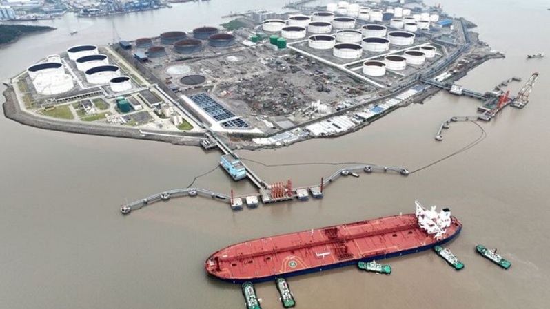 Pemandangan udara menunjukkan kapal tunda membantu sebuah kapal tanker minyak mentah untuk berlabuh di terminal minyak lepas Pulau Waidiao, Zhoushan, Provinsi Zhejiang, Tiongkok pada 18 Juli 2022. (FOTO: cnsphoto via REUTERS)