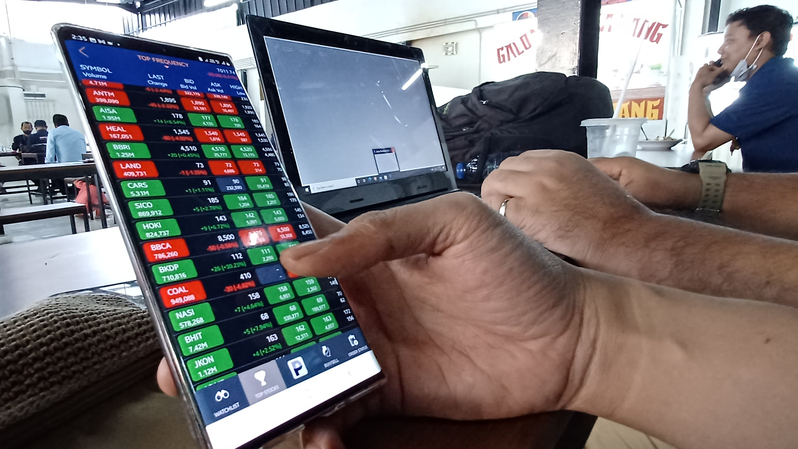 Investor memantau pergerakan saham lewat ponsel. (B Universe Photo/Uthan AR) 