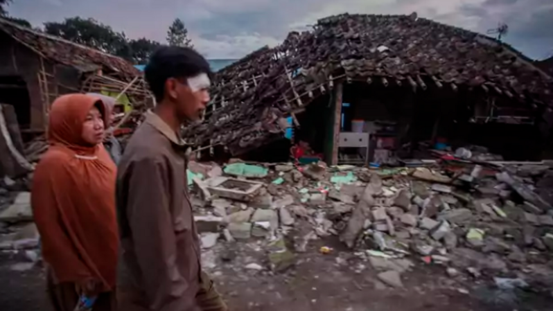 Warga melintas di depan rumahnya yang rusak akibat gempa di Desa Cibeureum, Kabupaten Cianjur, Jawa Barat, Senin, 21 November 2022. (Foto: Antara)