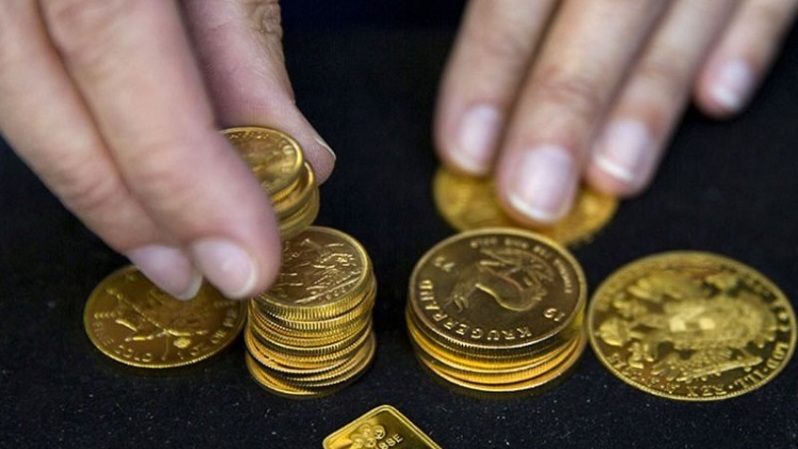 Pekerja memperlihatkan kepingan koin emas. (Foto: ANTARA/REUTERS/Neil Hall/aa)