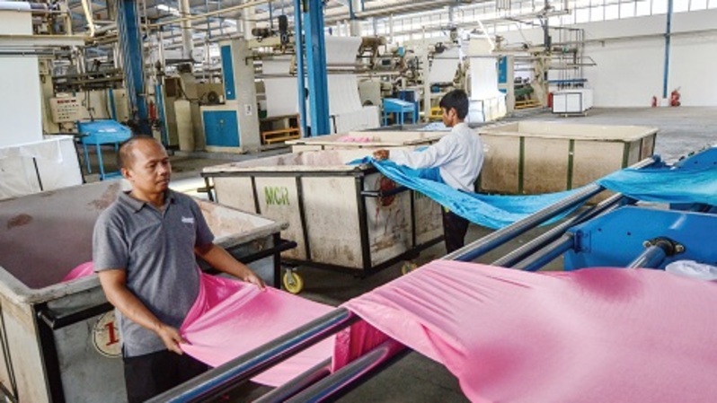 Pekerja memasukkan kain ke dalam mesin sebelum dikemas di Pabrik Industri Tekstil Nanjung, Cimahi, Jawa Barat.  Foto ilustrasi: Investor Daily/DAVID GITA ROZA