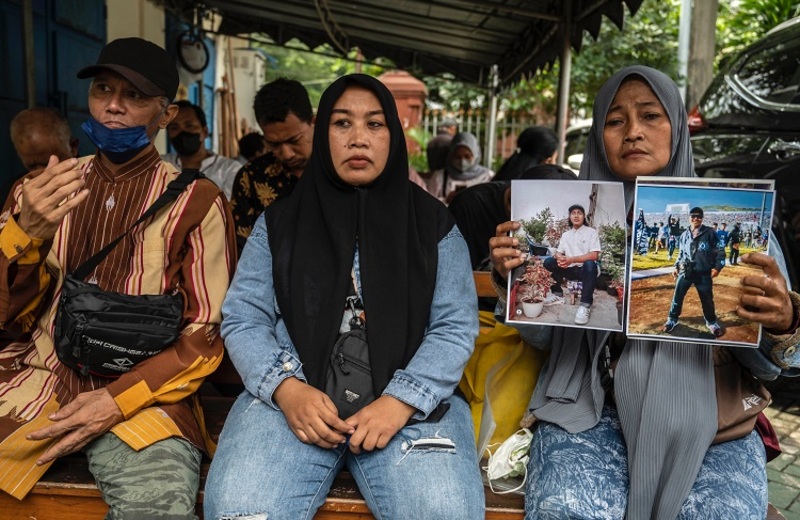 Rink Hanifah (kanan) menunjukkan foto mendiang putranya Agus Riansyah, salah satu dari 135 orang yang tewas dalam bencana stadion sepak bola Kanjuruhan 1 Oktober 2022, saat menghadiri persidangan di gedung pengadilan Surabaya pada 16 Januari 2023. (Foto: Juni Kriswanto/AFP)