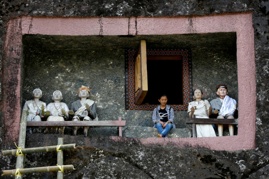 A visitor sits outside a burial chamber cut into a massive boulder of Loko'mata, a traditional Toraja burial site, during an ancient Torajan ritual known as 'Ma'nene.' (Reuters Photo/Darren Whiteside)