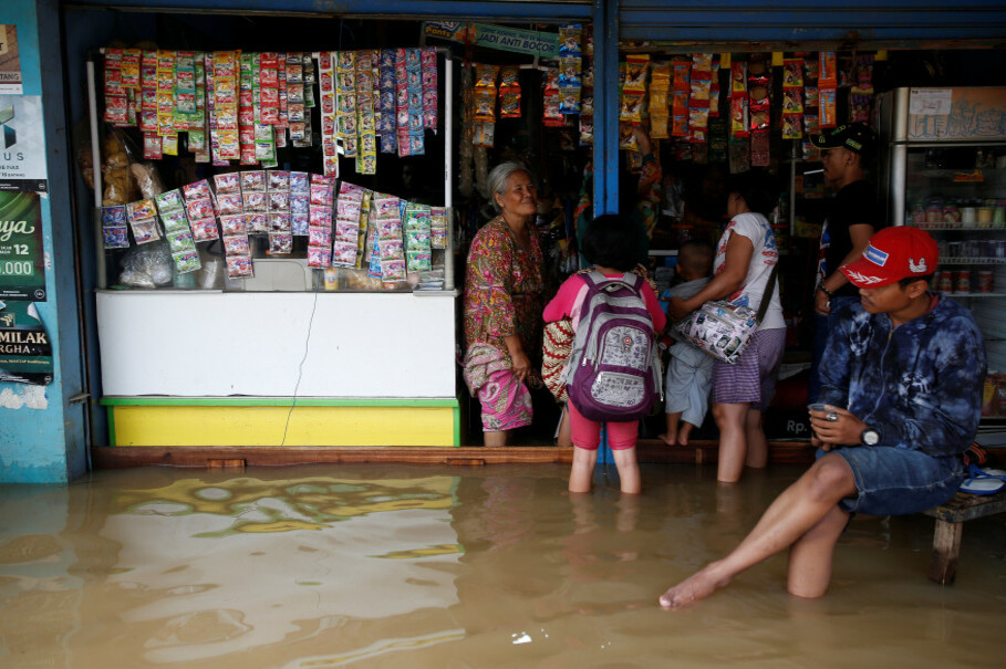 A shopkeeper chats with customers after heavy seasonal rains caused the Citarum River to flood Dayeuhkolot, south of Bandung, on Feb. 23. (Reuters Photo/Darren Whiteside)