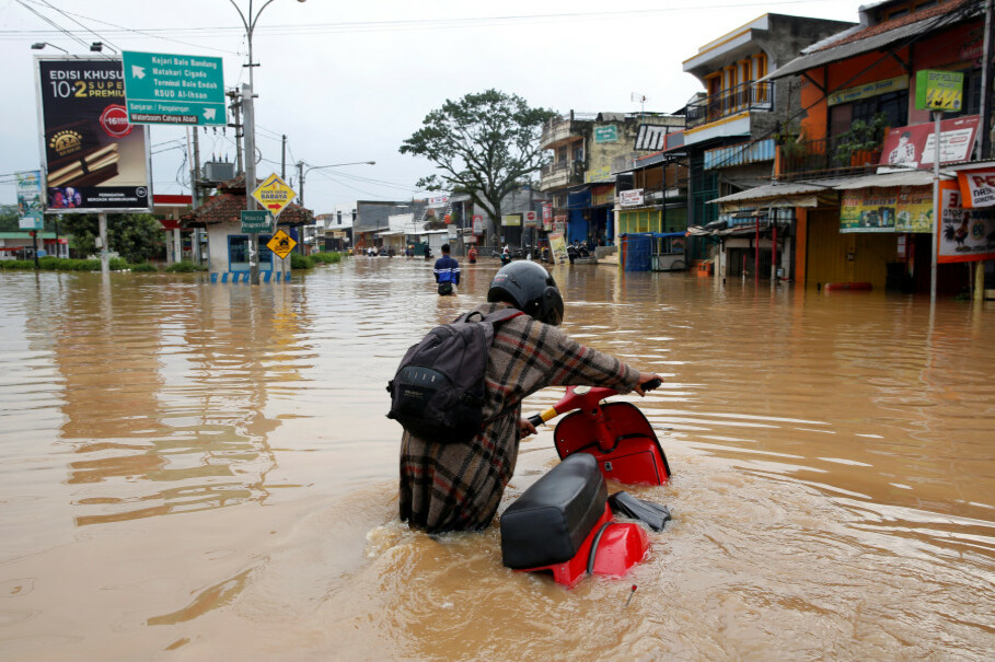 A woman pushes her scooter down a flooded street in Dayeuhkolot after the Citarum River burst its banks. (Reuters Photo/Darren Whiteside)