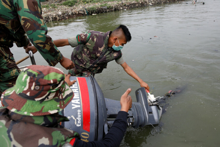 A soldier cuts away garbage wrapped around the propeller on a pontoon boat during a cleanup operation along the Citarum River, south of Bandung, on Feb. 13. (Reuters Photo/Darren Whiteside)
