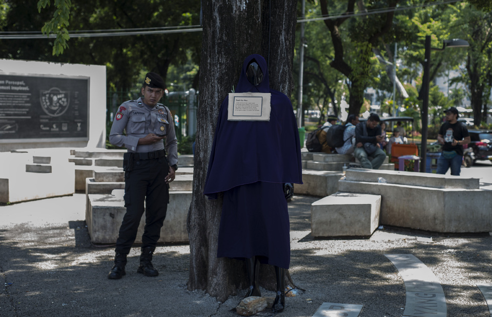 A policeman stands near a mannequin, used to send a message about sexual harassment and rape, in Aspiration Park in Central Jakarta. (JG Photo/Yudha Baskoro)