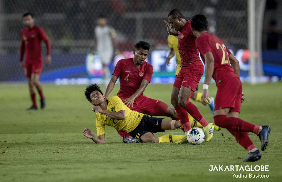 Malaysian forward Syafiq Ahmad goes down against Papua-born defender Yustinus Paew. (JG Photo/Yudha Baskoro) 