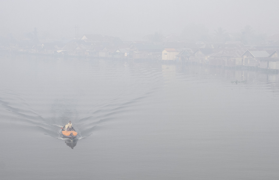 A motorboat crosses at Martapura River, which is shrouded with smoke haze in Banjarmasin, South Kalimantan on Thursday (12/09). (Antara Photo/Bayu Pratama S)