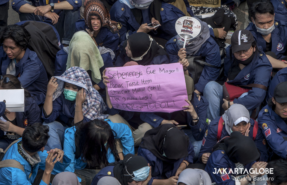 A protester carries a placard with a message criticizing the House of Representatives. (JG Photo/Yudha Baskoro) 