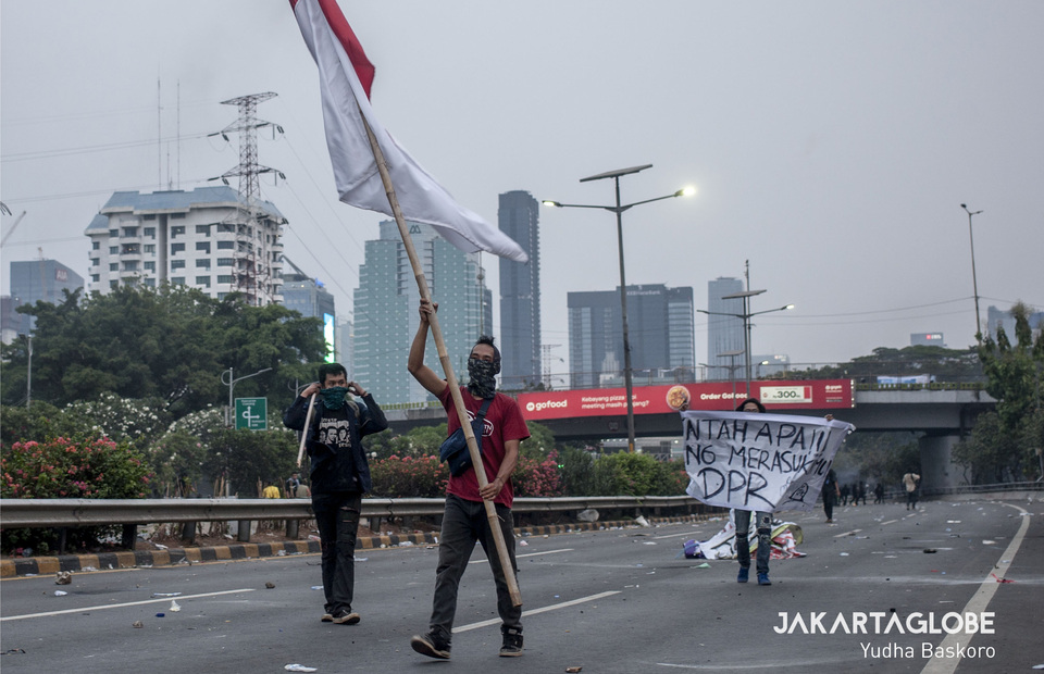 A protestor carries the national flag to signal an end to the riot. (JG Photo/Yudha Baskoro)