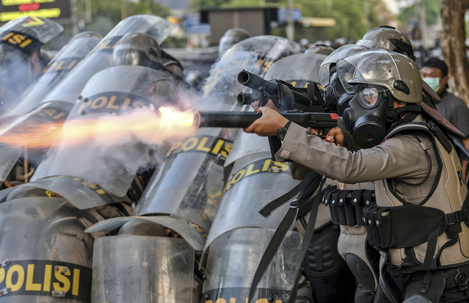 Police officer shoots tear gas to university students during 30 September riot in Gatot Subroto Street, Jakarta on Monday (30/09). (Antara Photo/Hafidz Mubarok A)