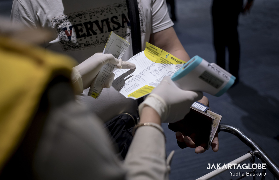 A health inspector at Soekarno-Hatta International Airport explains how to write the data on a yellow card to passengers who arrives from Hongkong. (JG Photo/Yudha Baskoro)