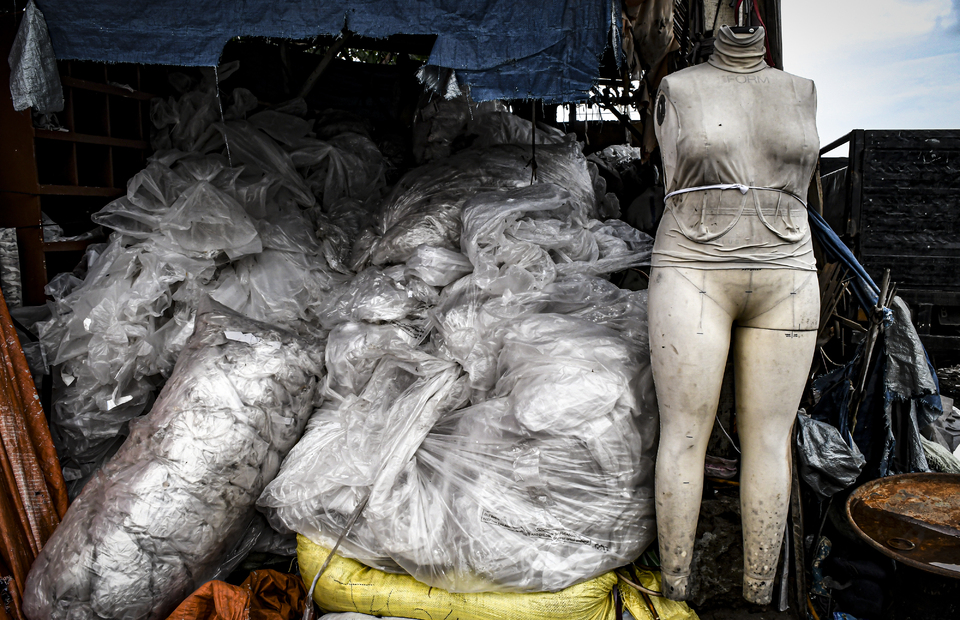 A mannequin is placed in between a pile of fashion waste