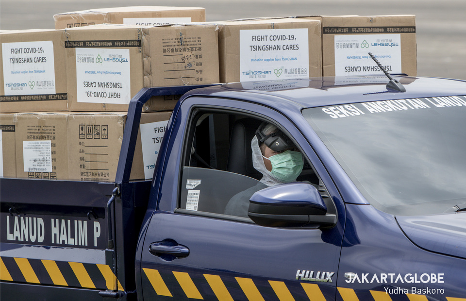 A driver wearing protective gear ride a car containing boxes of medical equipment from China in Halim Perdanakusuma Airforce Base, East Jakarta on Monday (23/03). (JG Photo/Yudha Baskoro)