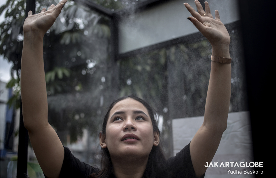 A woman uses the disinfection chamber for the first time as a basic preventive measure to new corona virus. (JG Photo/Yudha Baskoro)