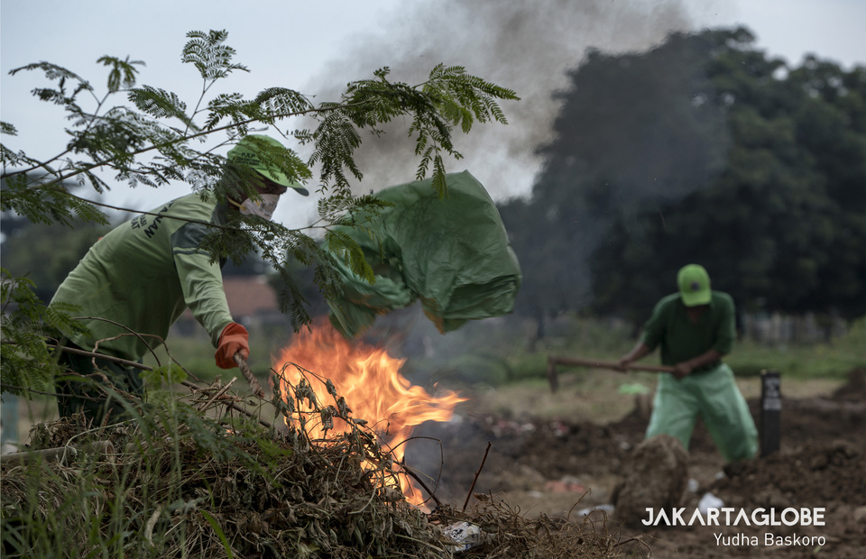 Funeral service workers burn their protective mask after perform a funeral in Tegal Alur public cemetery in West Jakarta on Thursday (26/03). (JG Photo/Yudha Baskoro)