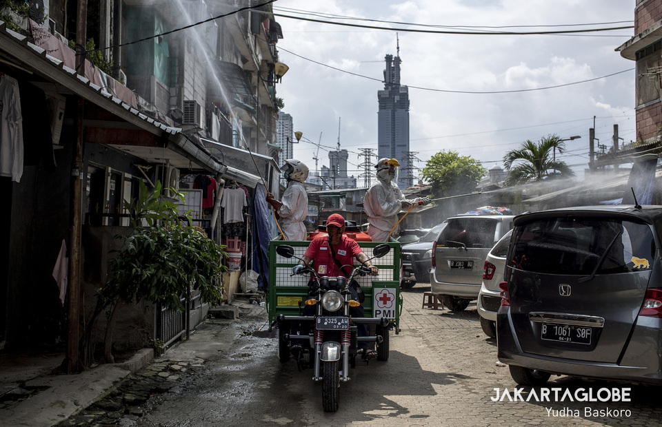 Two Red Cross personnels riding a mini dump truck spray the entire neighborhood in Rusun Petamburan with disinfectant. (JG Photo/Yudha Baskoro)