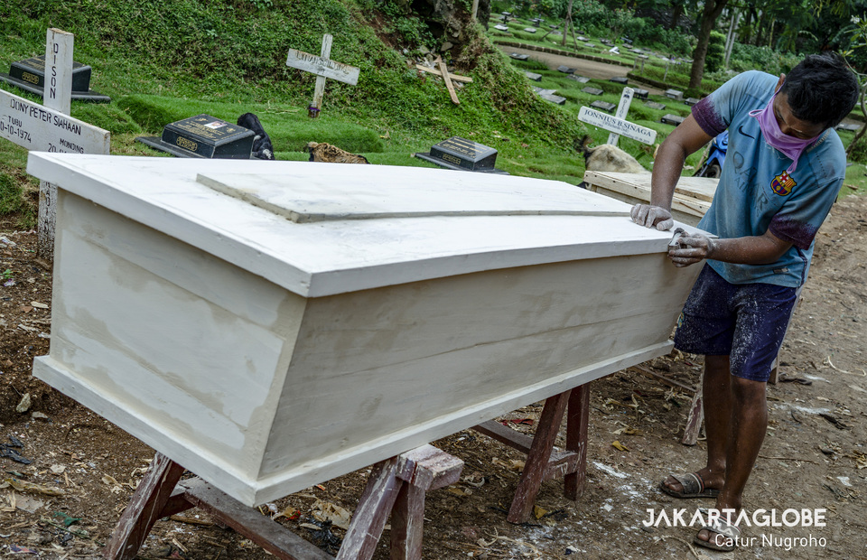 A coffin maker paints a coffin ordered to be donated for the coronavirus disease (COVID-19) victims. (JG Photo/Catur Nugroho)