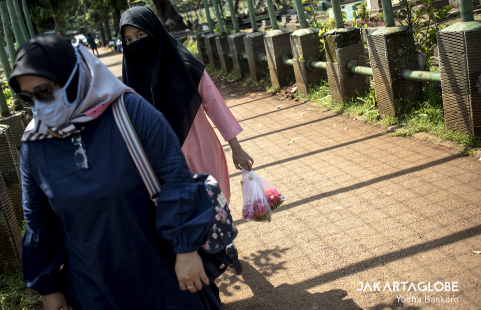 A woman brings two bags of flower at Karet Tengsin public cemetery in Central Jakarta on Wednesday (22/04). (JG Photo/Yudha Baskoro)