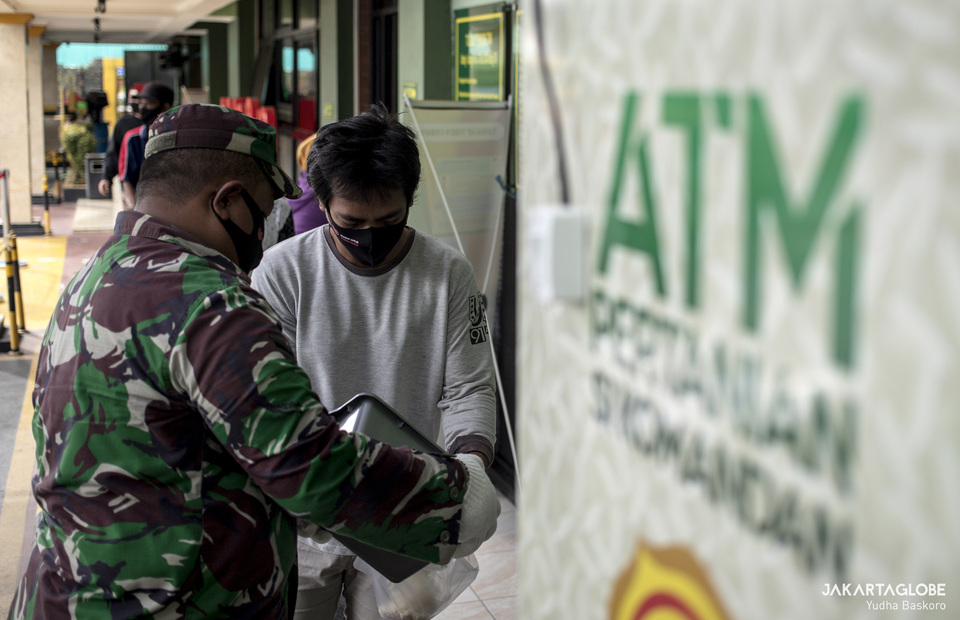 Indonesian army personnel help a resident to put a rice in a plastic bag. (JG Photo/Yudha Baskoro)