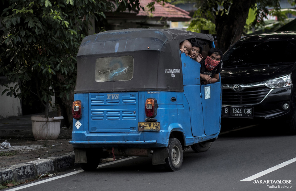 A bajaj driver and his children are waiting for their turn to get free takjil. (JG Photo/Yudha Baskoro)