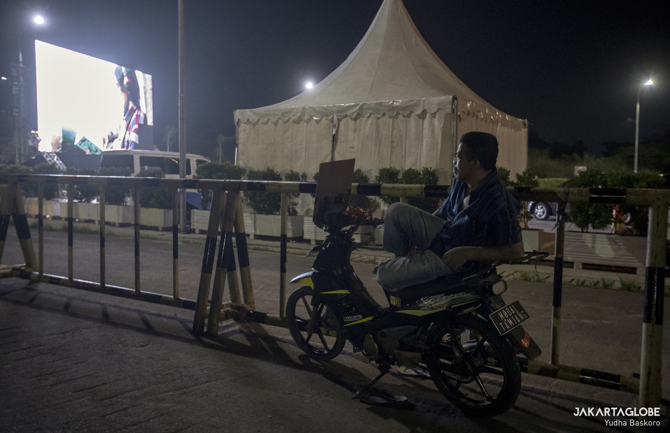 Motorcycle taxi driver enjoying screening from the outside of parking area. (JG Photo/Yudha Baskoro)