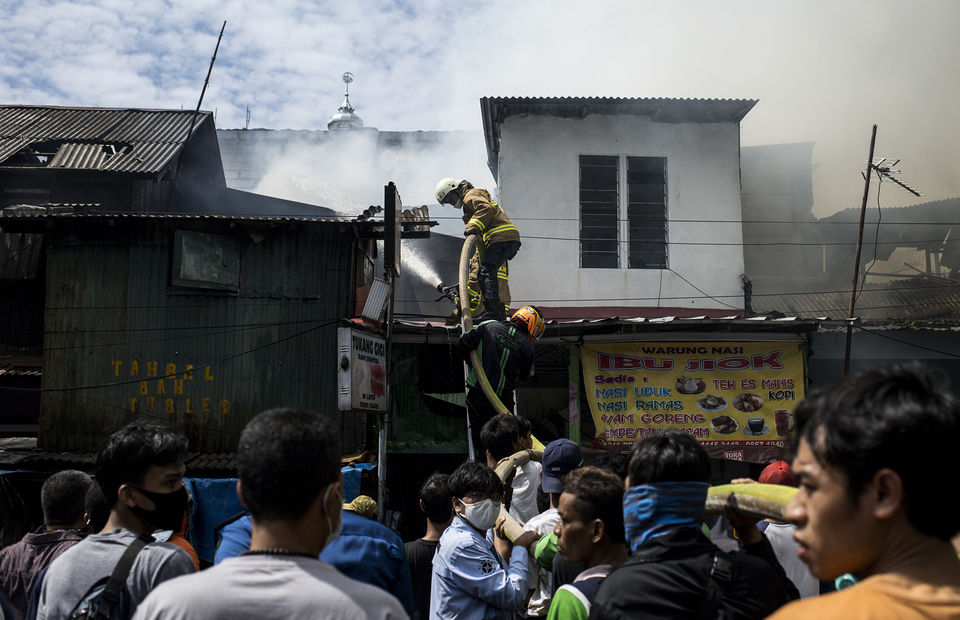 Fire fighters climb a burning building during fire in Manggarai, South Jakarta on Tuesday (07/07). (JG Photo/Yudha Baskoro)