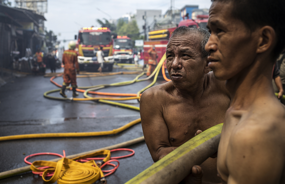 Two residents try to extinguish the fire in Manggarai, South Jakarta on Tuesday (07/07). (JG Photo/Yudha Baskoro)