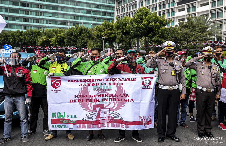 Police personnels and online taxi drivers give salute to Indonesian flag during moment of silence to commemorate Indonesian declaration of independence in Hotel Indonesia roundabout at Central Jakarta on Monday (17/08). (JG Photo/Yudha Baskoro)