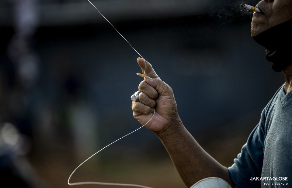 A man holds benang gelasan as he plays kite at Menteng Atas, South Jakarta on Thursday (28/08). (JG Photo/Yudha Baskoro)