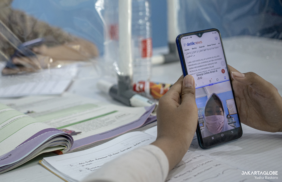 A student reads Quran through her smartphone during long-distance learning at Citizens Hall in Galur, Johar Baru, Central Jakarta on Thursday (03/09). (JG Photo/Yudha Baskoro) 