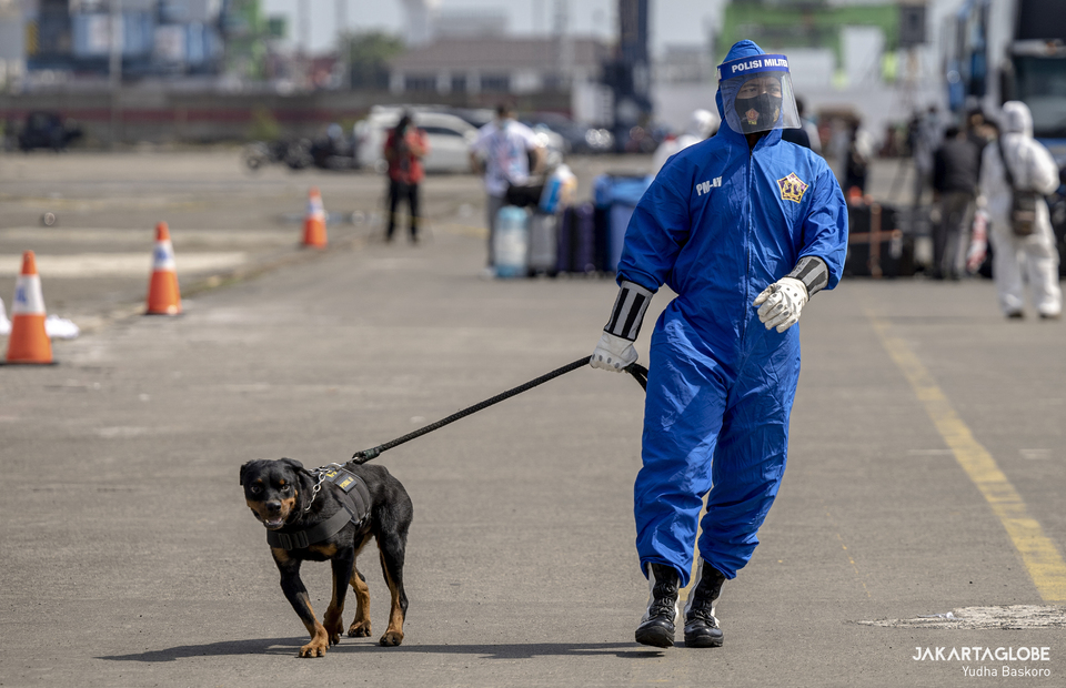 A military police personnel carries K9 dog during evacuation process at JICT II Pier, Tanjung Priok Port, North Jakarta on Tuesday (06/10). (JG Photo/Yudha Baskoro)