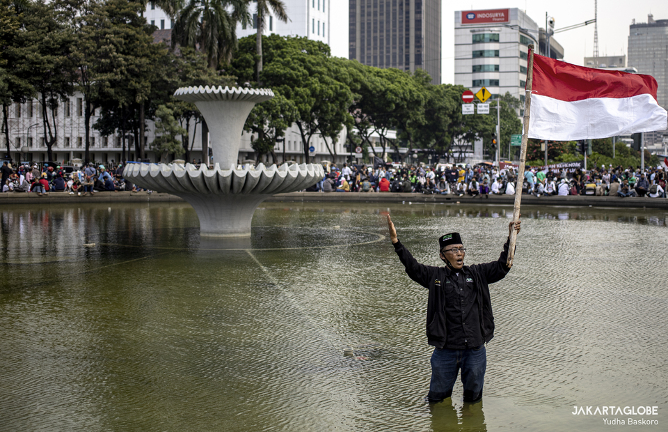 A protesters waves Indonesian flag during riot in Arjuna Wiwaha Horse Statue in Central Jakarta on Tuesday (13/10). (JG Photo/Yudha Baskoro)