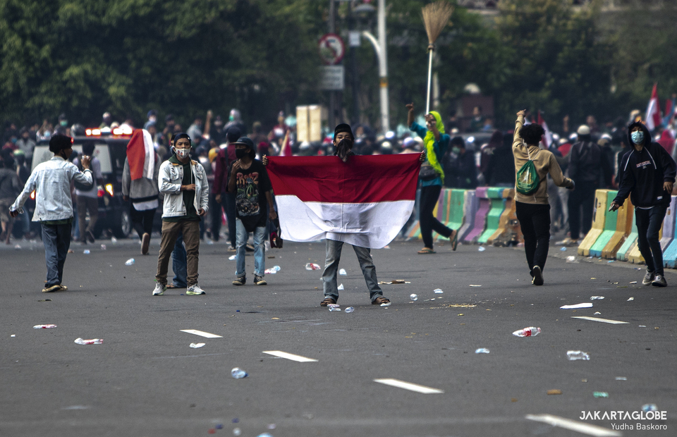A protester carries Indonesian flag during riot in Arjuna Wiwaha Horse Statue in Central Jakarta on Tuesday (13/10). (JG Photo/Yudha Baskoro)