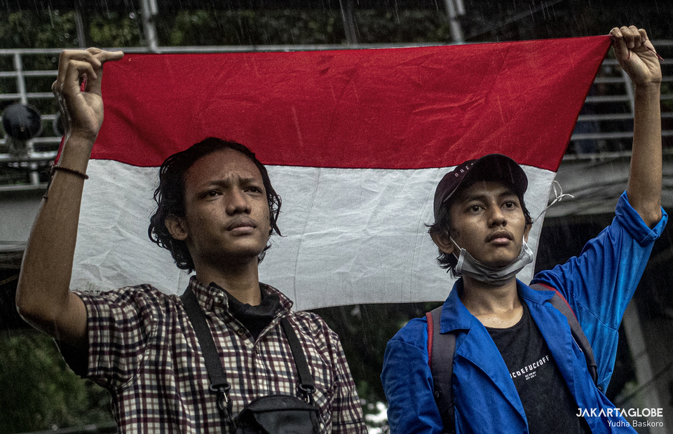 Two protesters hold Indonesian flag together during protest in Arjuna Wiwaha Horse Statue in Central Jakarta on Friday (16/10). (JG Photo/Yudha Baskoro)