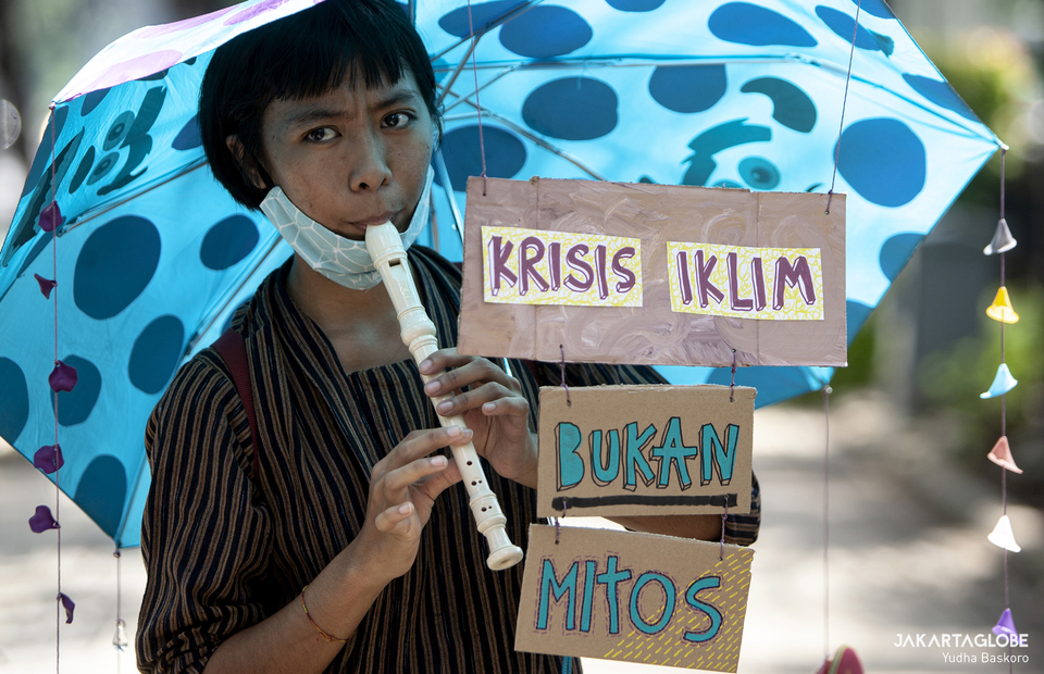 Climate activist plays flute during protest in front of Jakarta City Hall on Friday (27/11). (JG Photo/Yudha Baskoro)