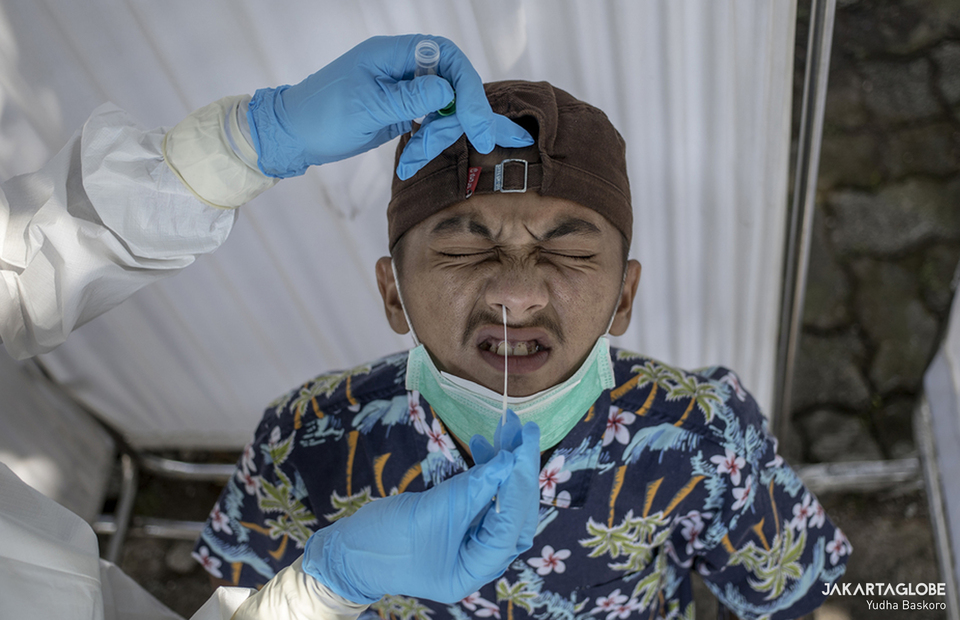 A health worker takes a swab from a man during a Covid-19 test at the Pluis traditional market in West Jakarta on Wednesday. (JG Photo/Yudha Baskoro)