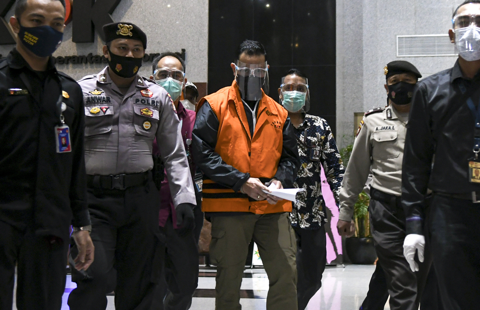 Juliari walks at the Corruption Eradication Commission (KPK) building on December 7, 2020, wearing mask and the trademark orange vest worn by KPK detainees with several KPK officers accompanying him. Social Affairs Minister Juliari Peter Batubara has turned himself in on Sunday after the anti-corruption agency named him as a suspect in a graft case related to the government
